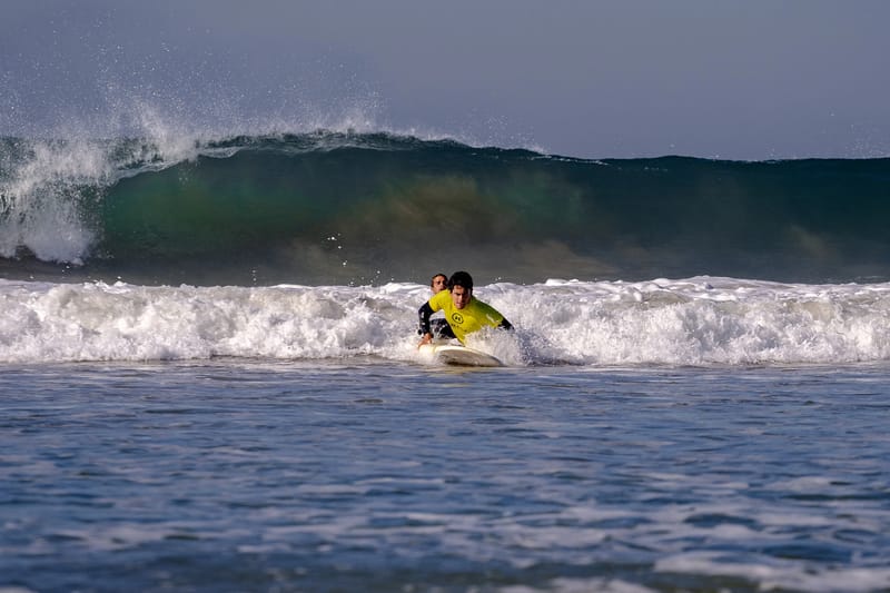Surf lesson at Praia da Saúde with student paddling into a wave